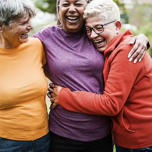 Three women smiling and hugging
