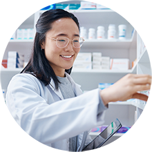 A pharmacist organizing medication bottles on a shelf in the pharmacy