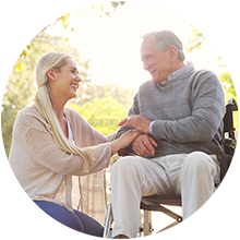 A daughter holding the hand of her elderly father in a wheelchair