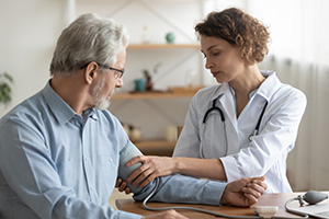 A physician checking the heart rate of a senior male