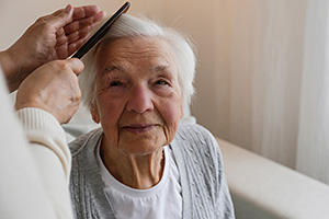 A senior woman getting her hair combed by another person