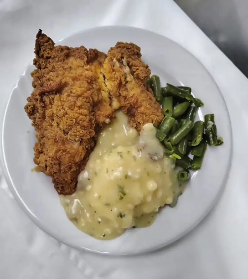 A plate of fried chicken, mashed potatoes, and green beans at Autumn Wind